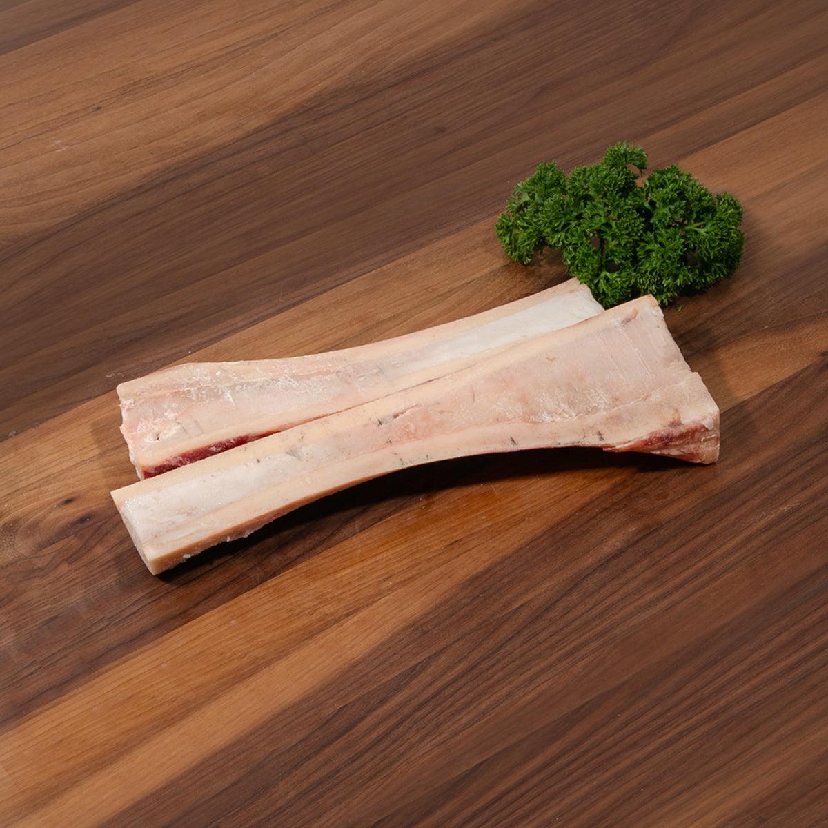 Frozen beef marrow bone pieces, pale bone with reddish marrow and fat
