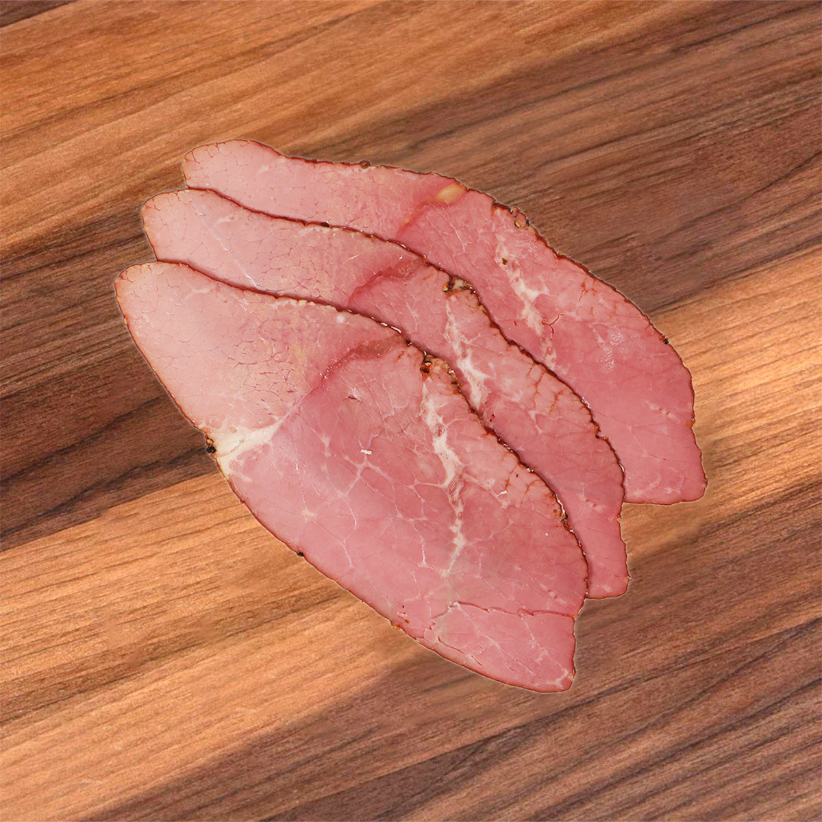 Sliced corned beef round, pink and marbled with visible seasoning specks.