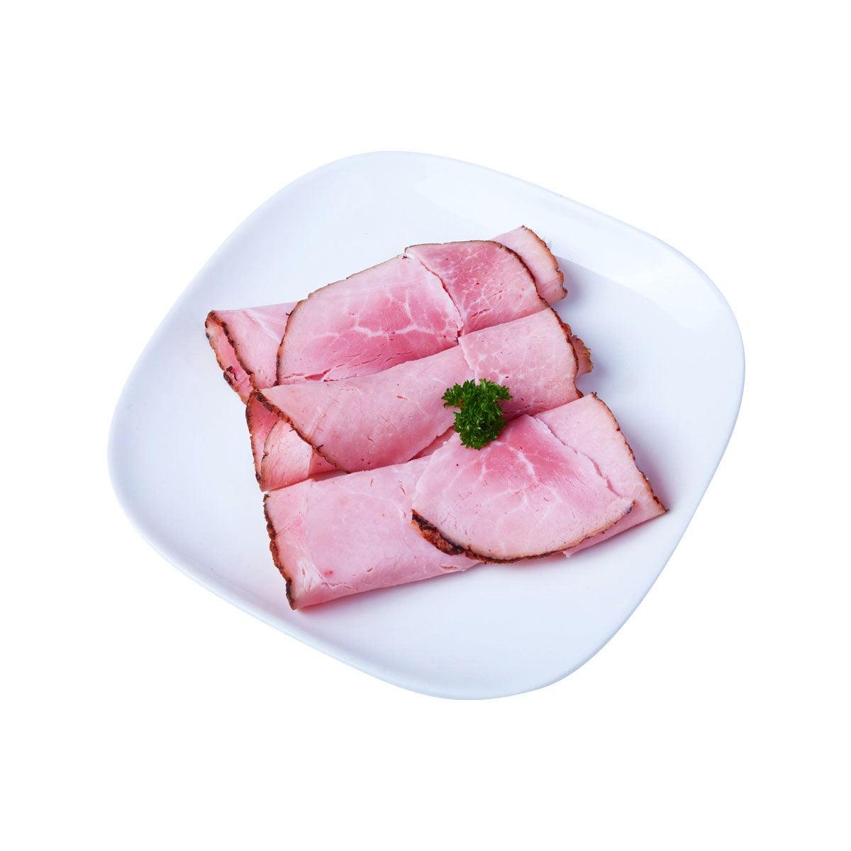 Smoked ham slices on a white plate, pink with dark edges