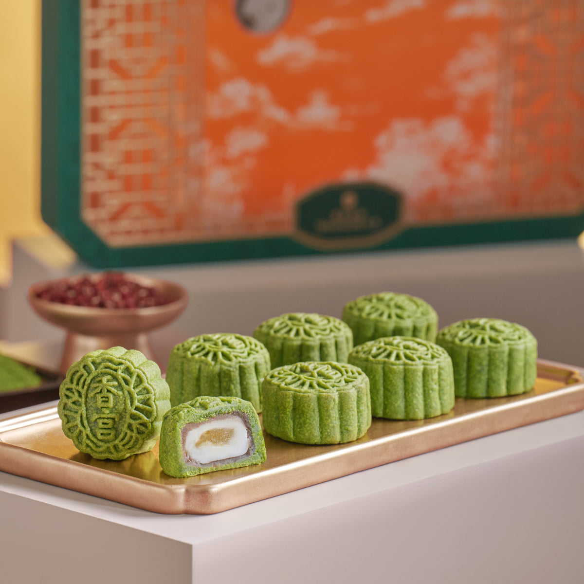 Green matcha mini mooncakes on a tray, with one piece showing white filling