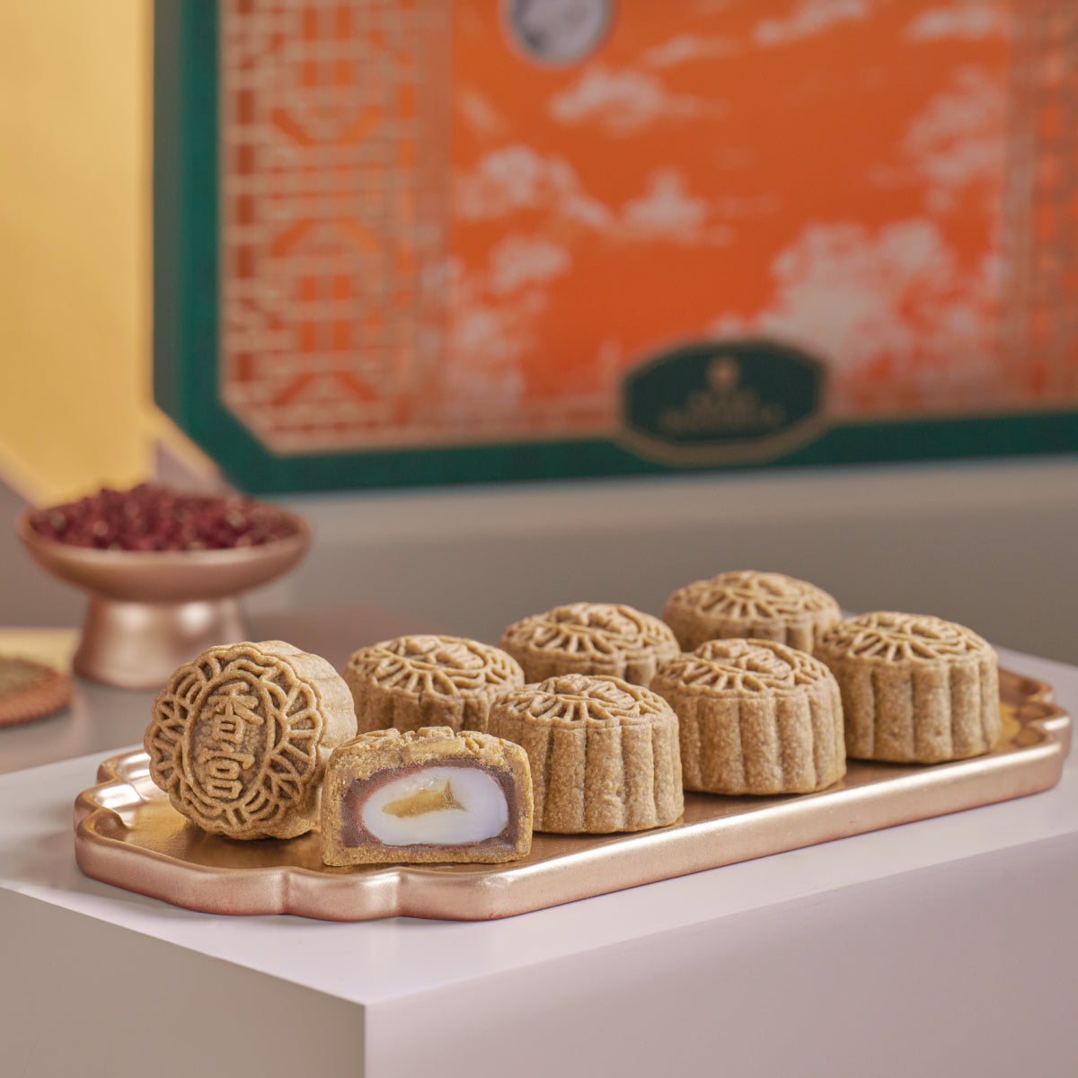 Mini mooncakes on a gold tray, with one sliced showing red bean and yuzu filling.