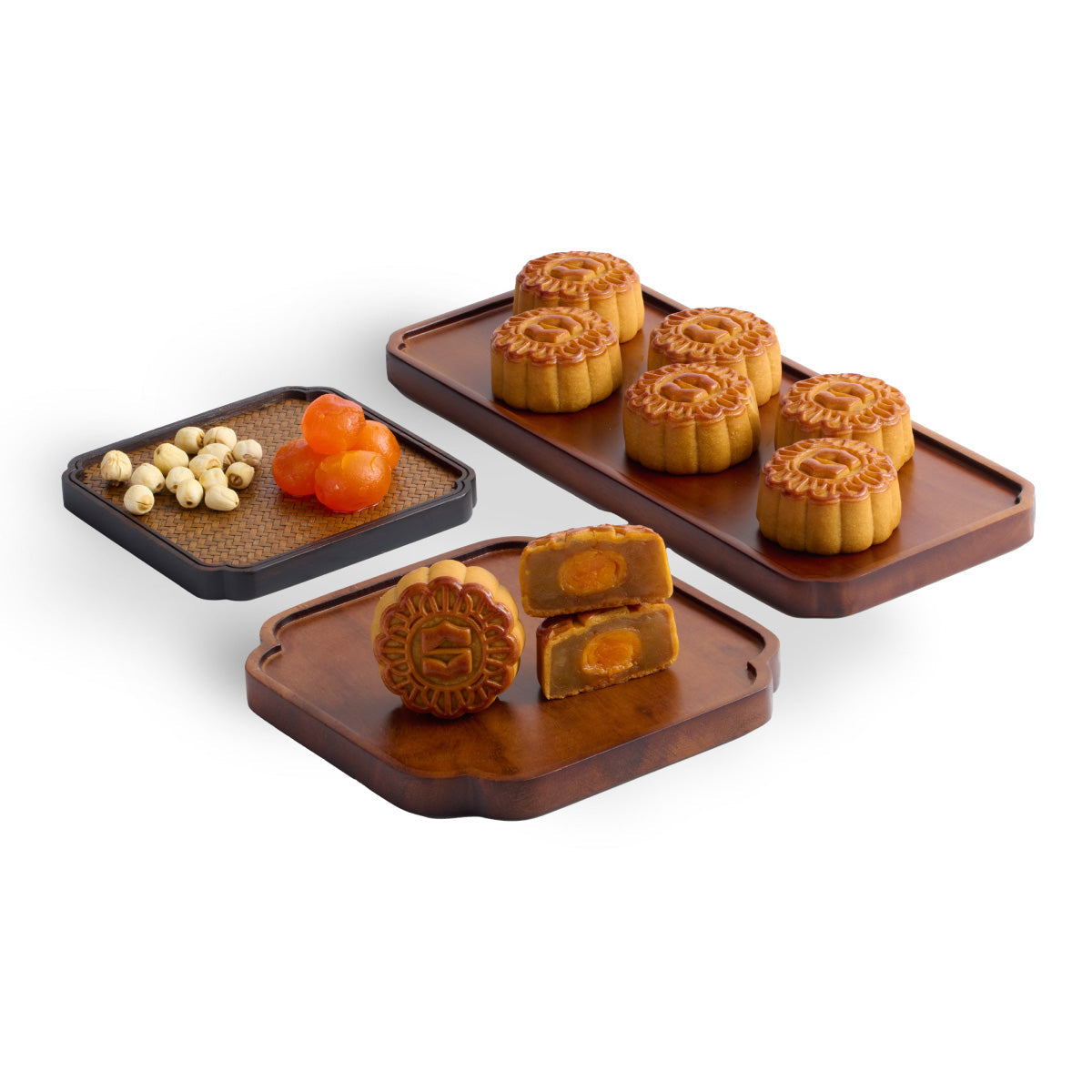Assorted mini mooncakes on dark trays, with patterned tops and cut slices showing yolk