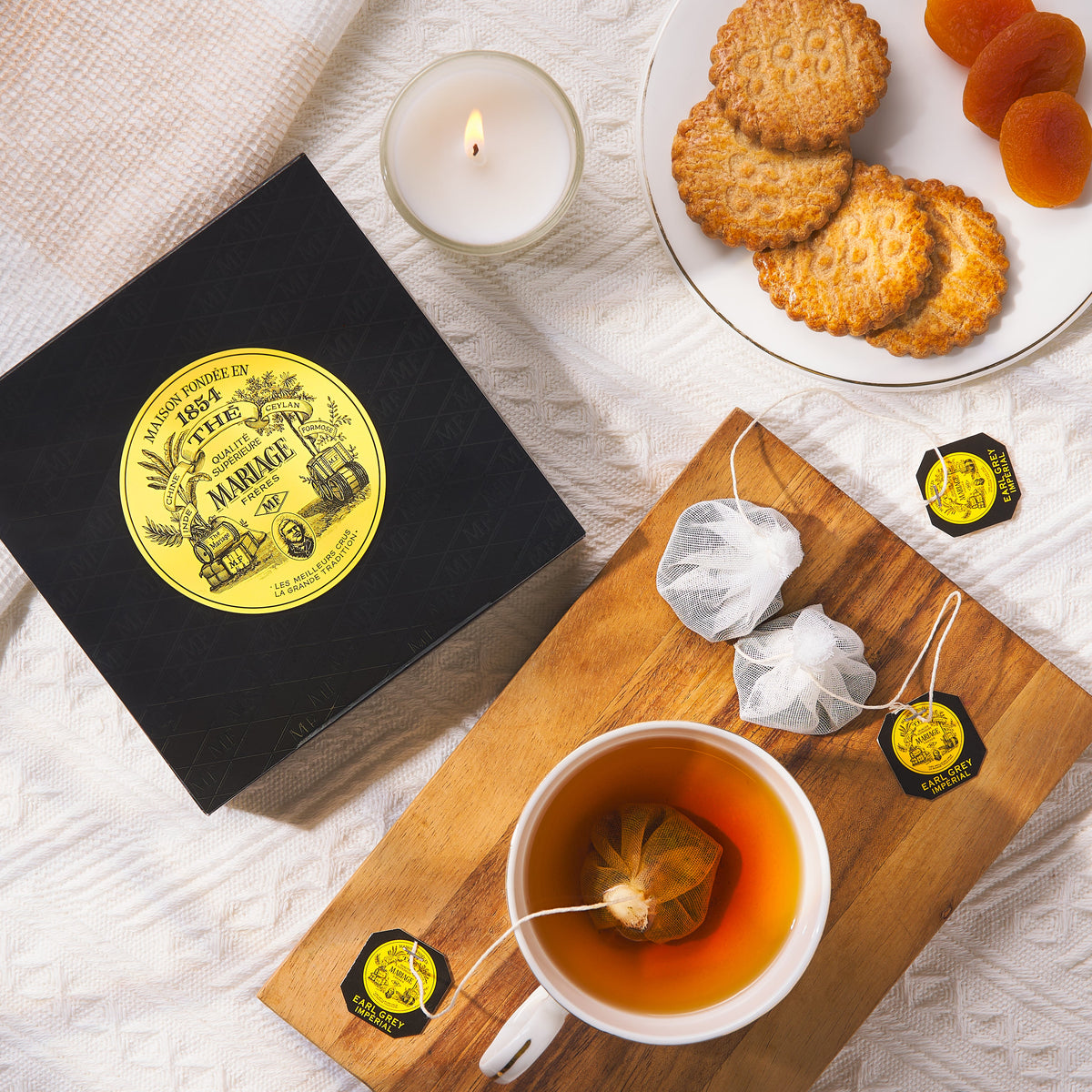 Earl Grey tea bags with black box, cup of tea, and sealed sachets