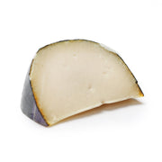 Firm goat milk cheese wedge, pale ivory interior with dark rind
