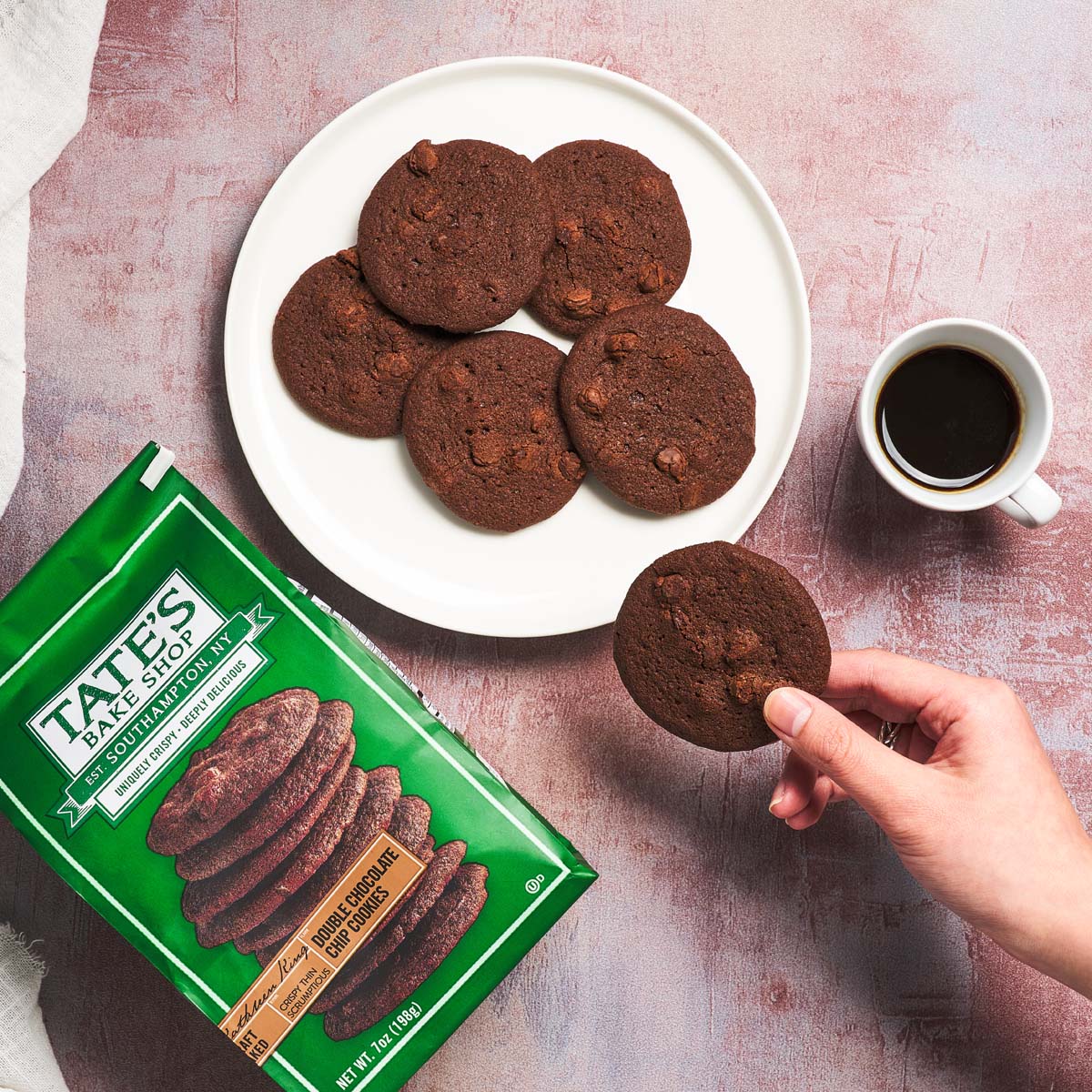 TATE'S double chocolate chip cookies: dark cookies on white plate, one held near cup