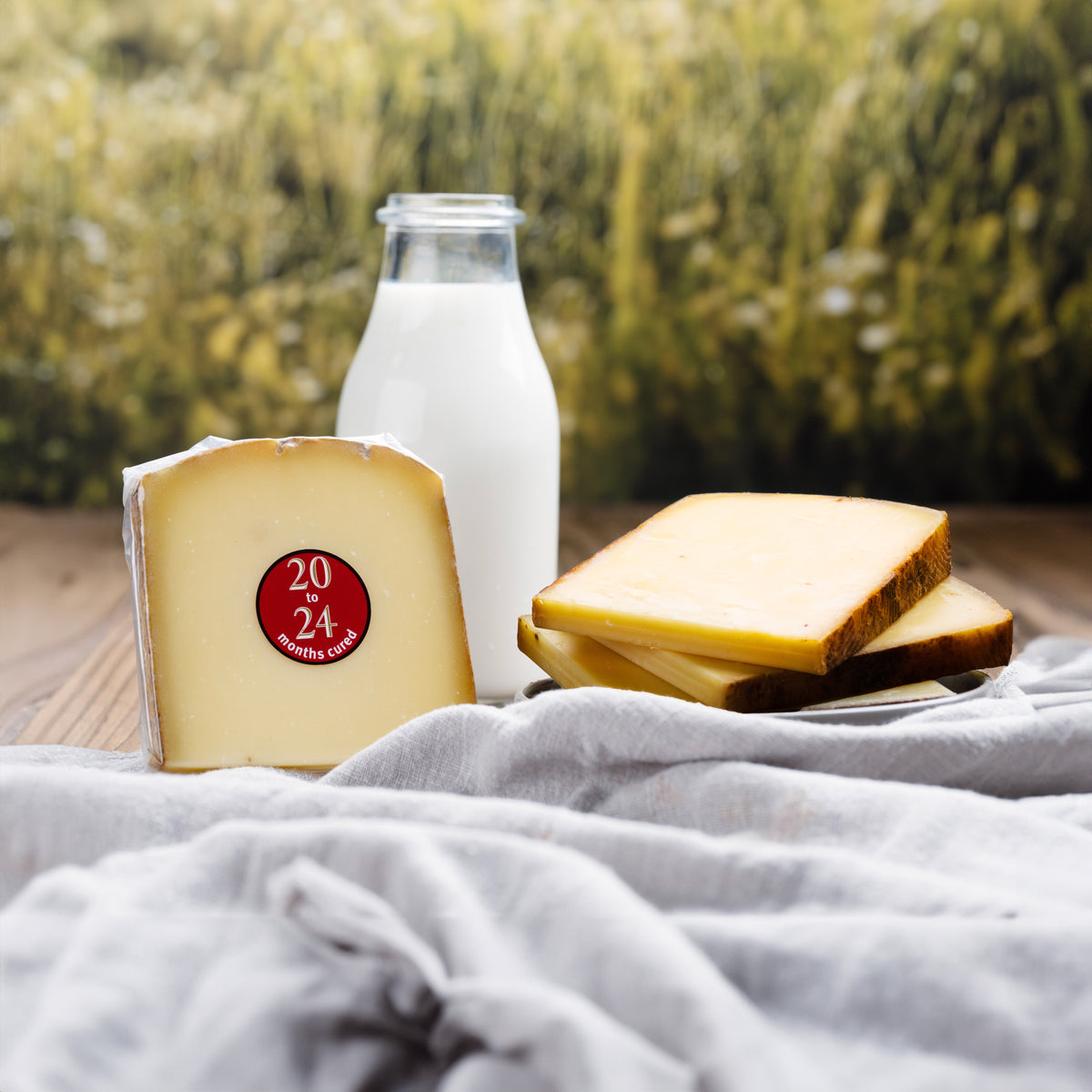 Raw milk Comte cheese wedge with red stamp on rind; sliced pieces on cloth