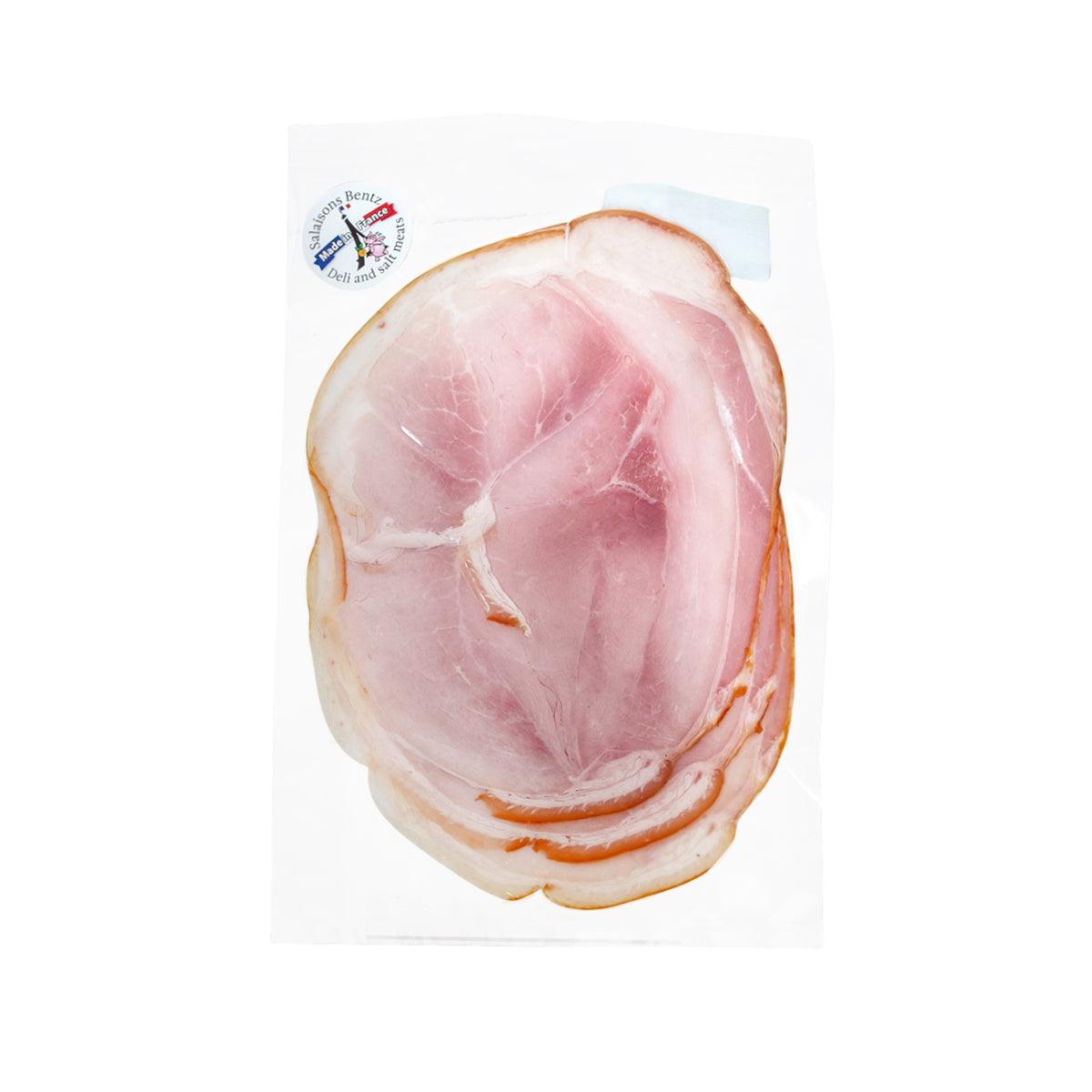 Half-cut smoked cooked ham slice with rind, pink interior and browned outer edge