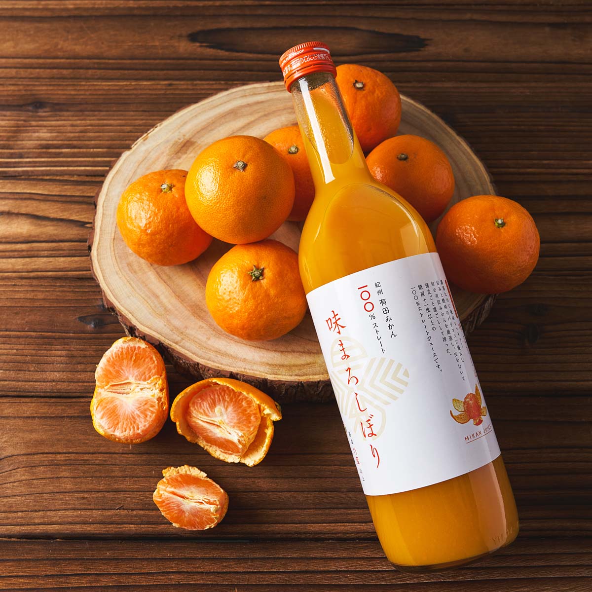 Mikan juice bottle with orange cap on wooden board with mikan oranges