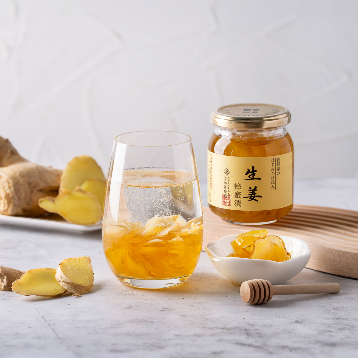 Sliced ginger in honey jar with ginger pieces, served with a glass of golden liquid