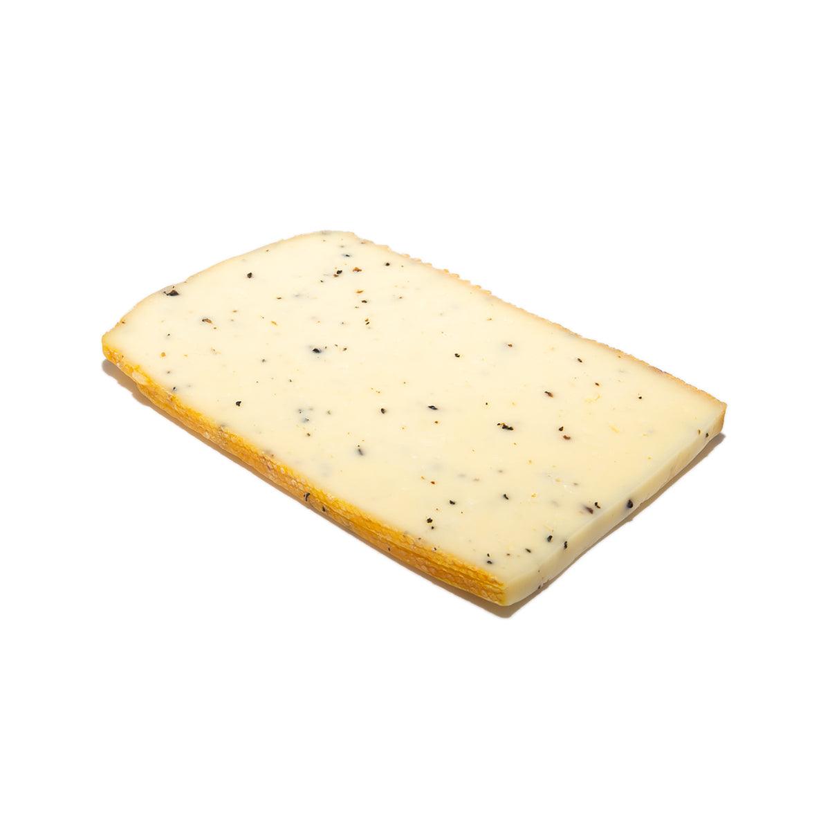 Raw milk raclette truffle cheese slice, pale yellow with black specks