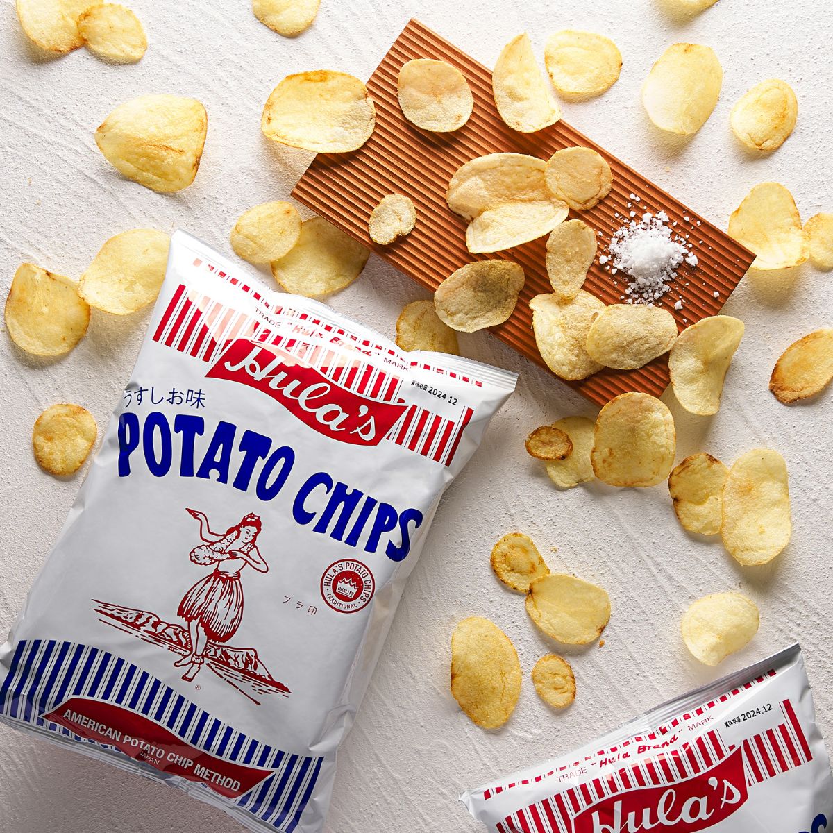 Potato chips bag with scattered chips and wooden scoop, light salt seasoning