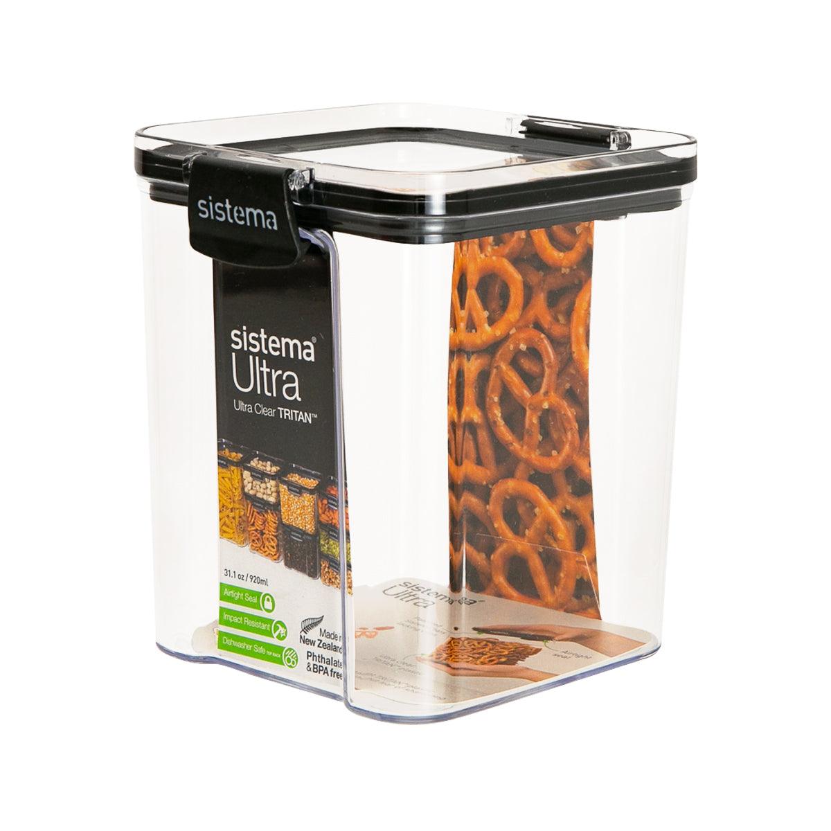 Square clear plastic food container with black lid, filled with orange food