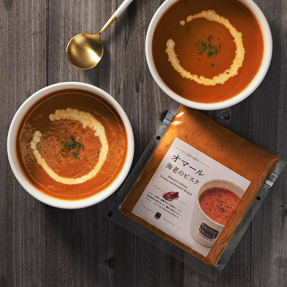 Lobster bisque in bowls with garnish, and soup packet on wooden table
