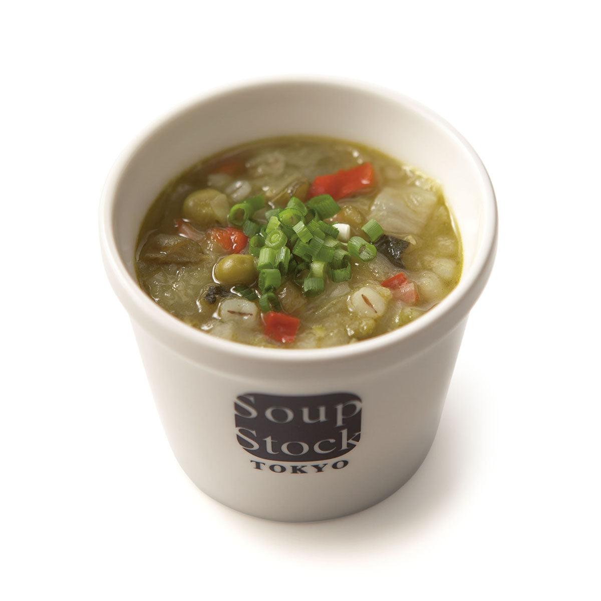 Cup of green vegetable minestrone soup topped with scallions and diced vegetables