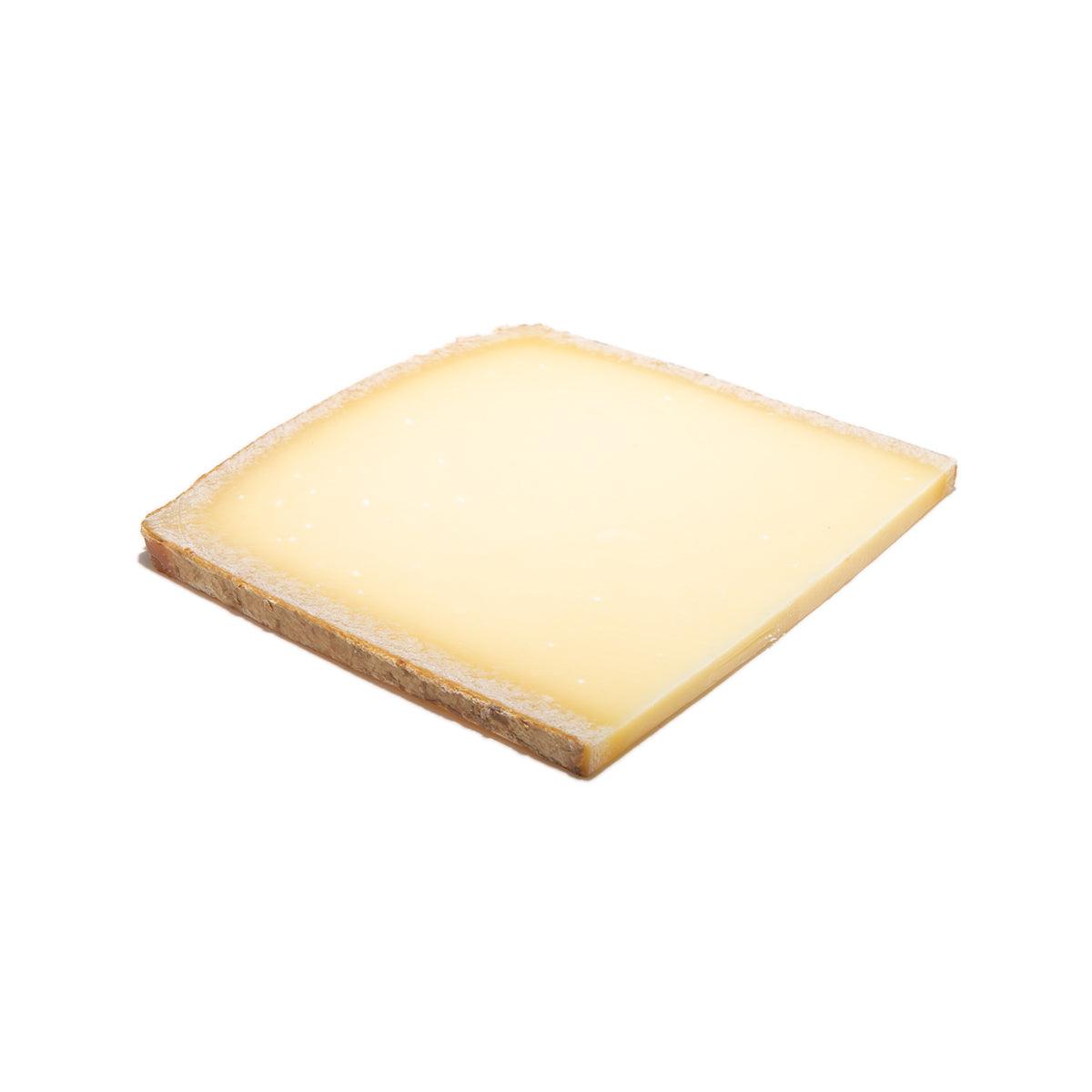 Aged Gruyere cheese wedge with pale yellow interior and light brown rind