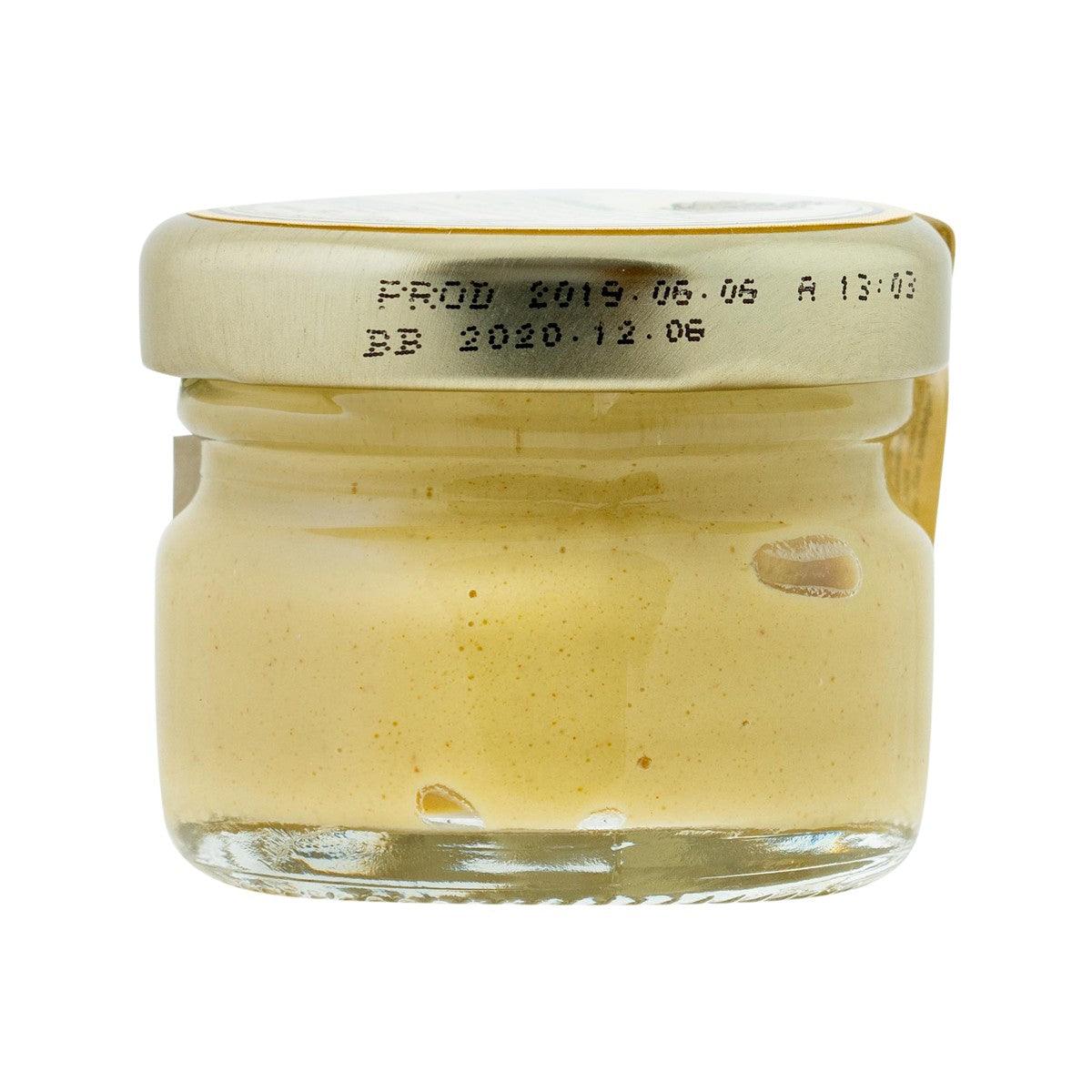 Small glass mustard jar with pale yellow mustard and cream-colored lid.