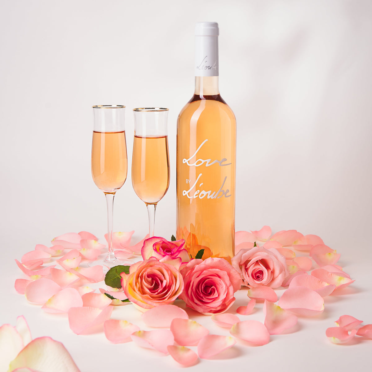 Wine bottle with two pink glasses, rose bouquet, and light pink liquid