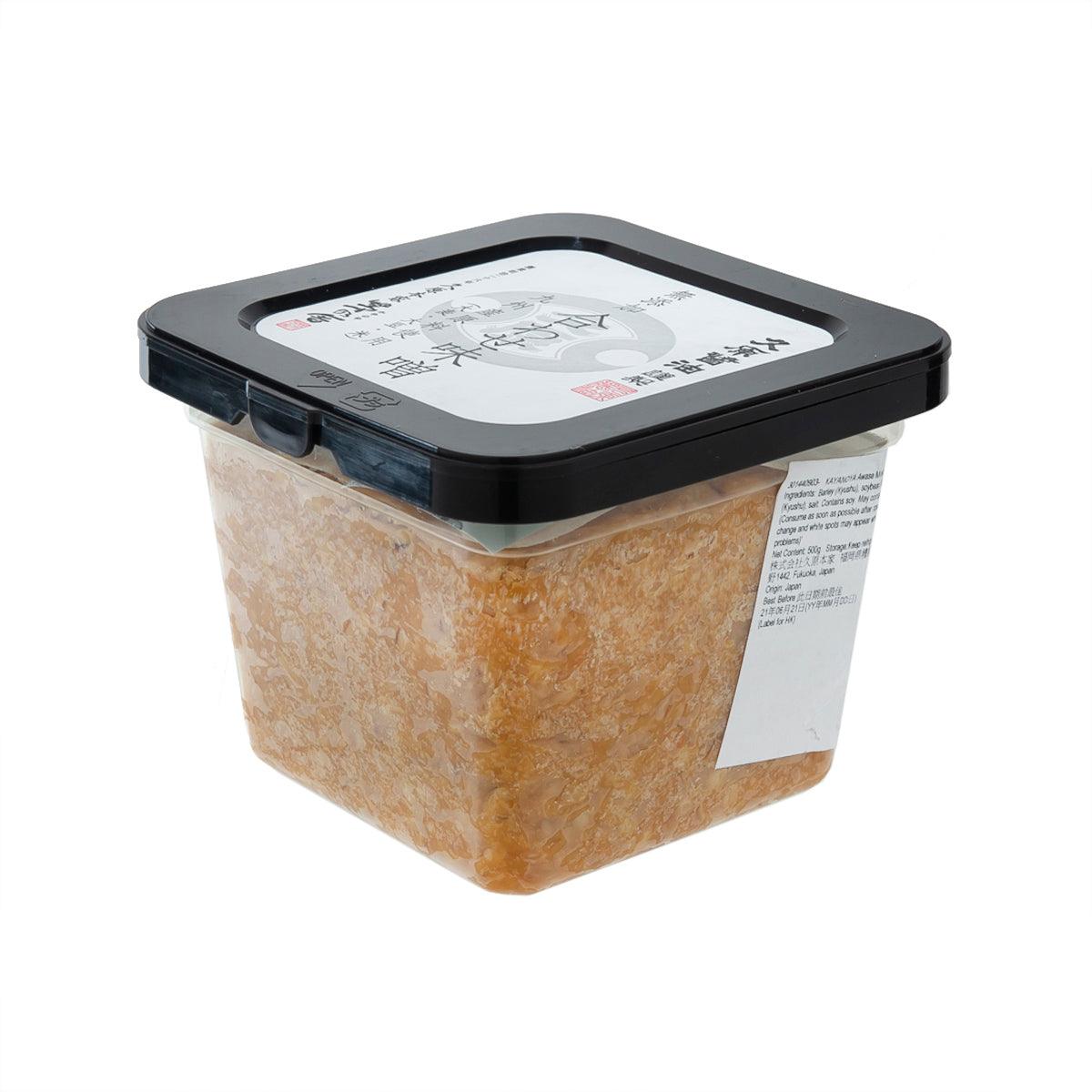 Miso paste tub with black lid and amber-beige paste visible through sides