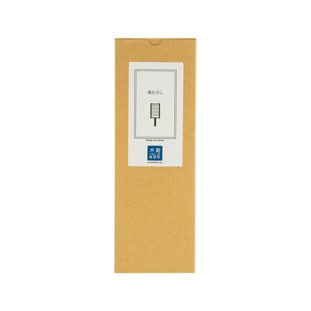 Wooden grater in cardboard packaging with label showing grater blade icon