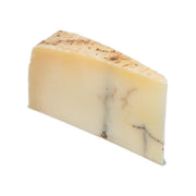 Sheep's milk truffle cheese wedge, pale with dark truffle specks and smooth rind