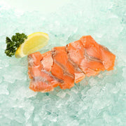 Smoked trout fillet pieces, orange-pink, on a tray