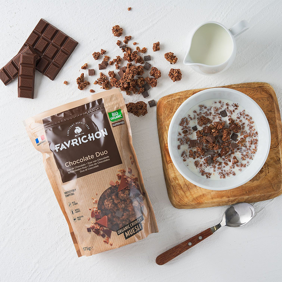 Organic gluten-free chocolate duo muesli with bowl, milk, spoon, and chocolate pieces