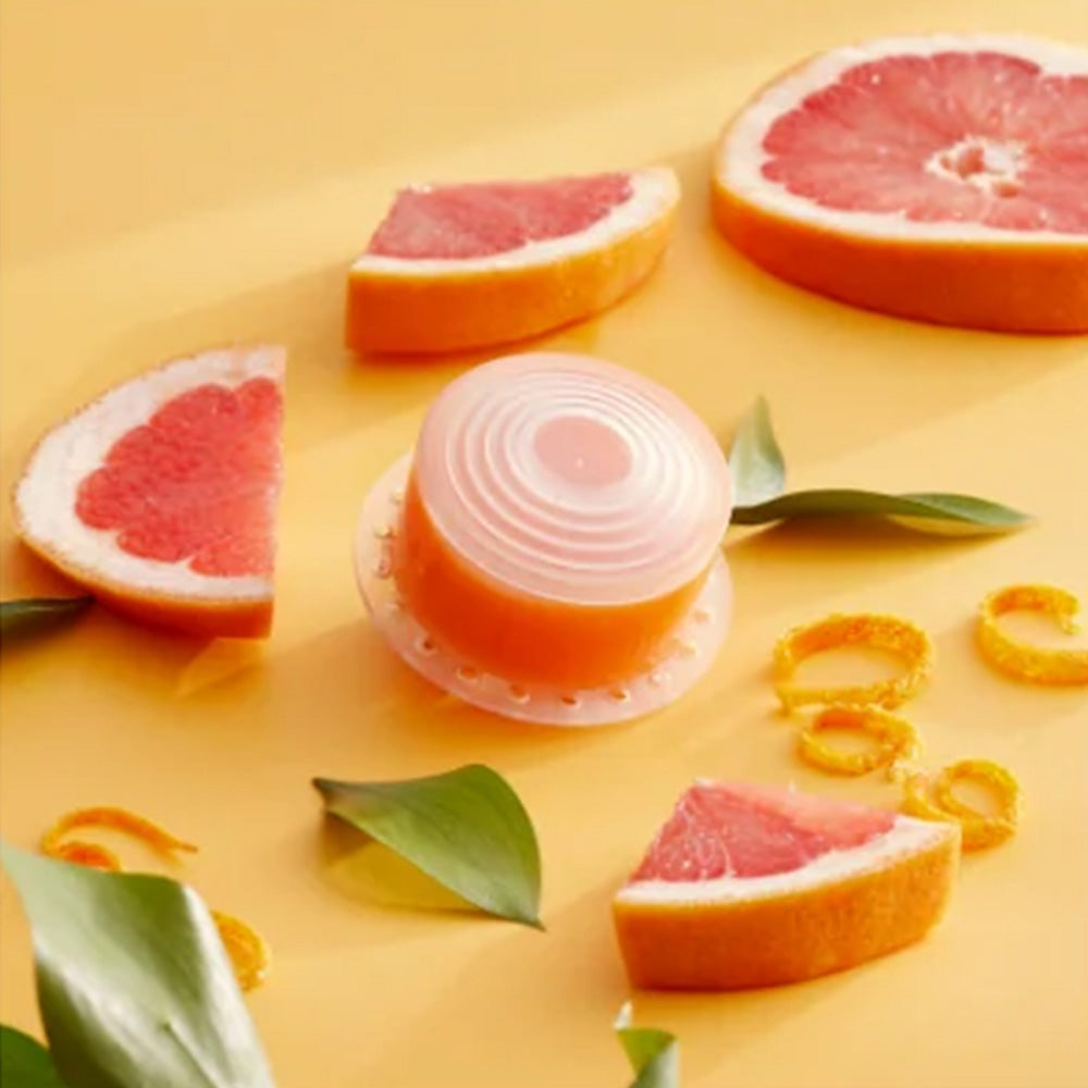 Round translucent shower head filter with orange core, on citrus fruit slices
