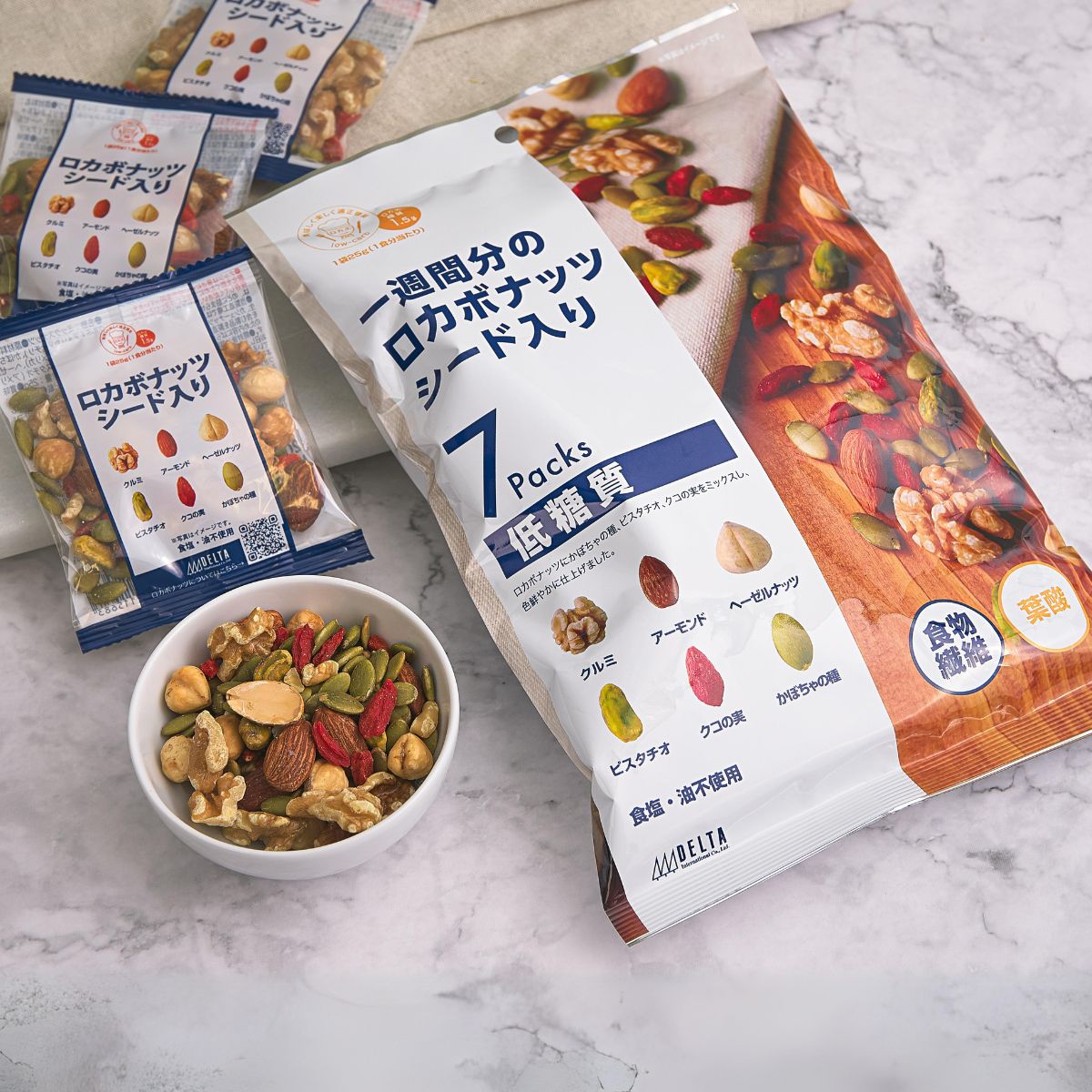 DELTA low-carb nut snack pouches with mixed-nuts bowl on a marble surface