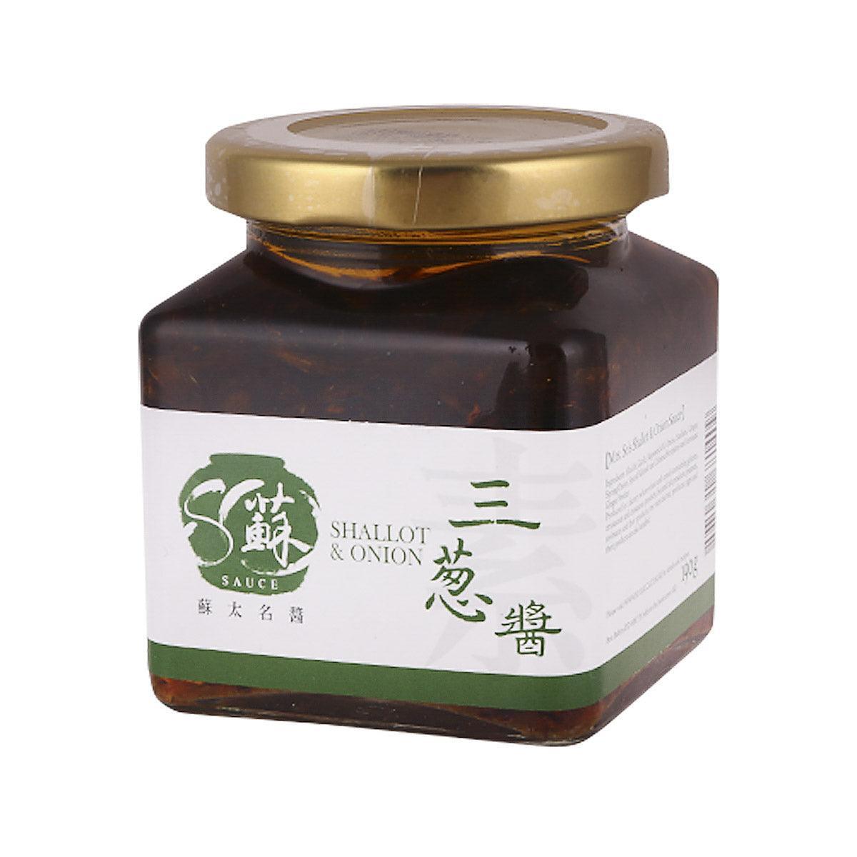 Jar of shallot and onion sauce with gold lid and white back label on dark glass.
