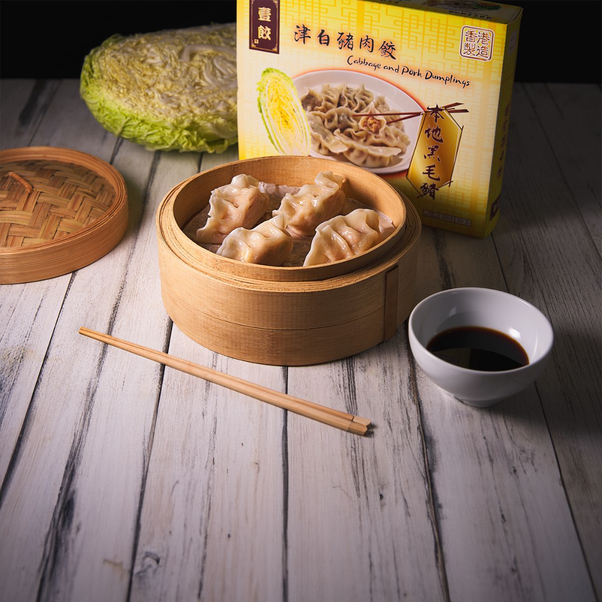 Steamed cabbage and pork dumplings in bamboo steamer with dipping sauce