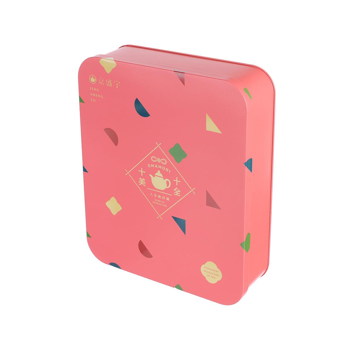 Pink square tea tin with omamori-themed emblem and geometric accents, side view