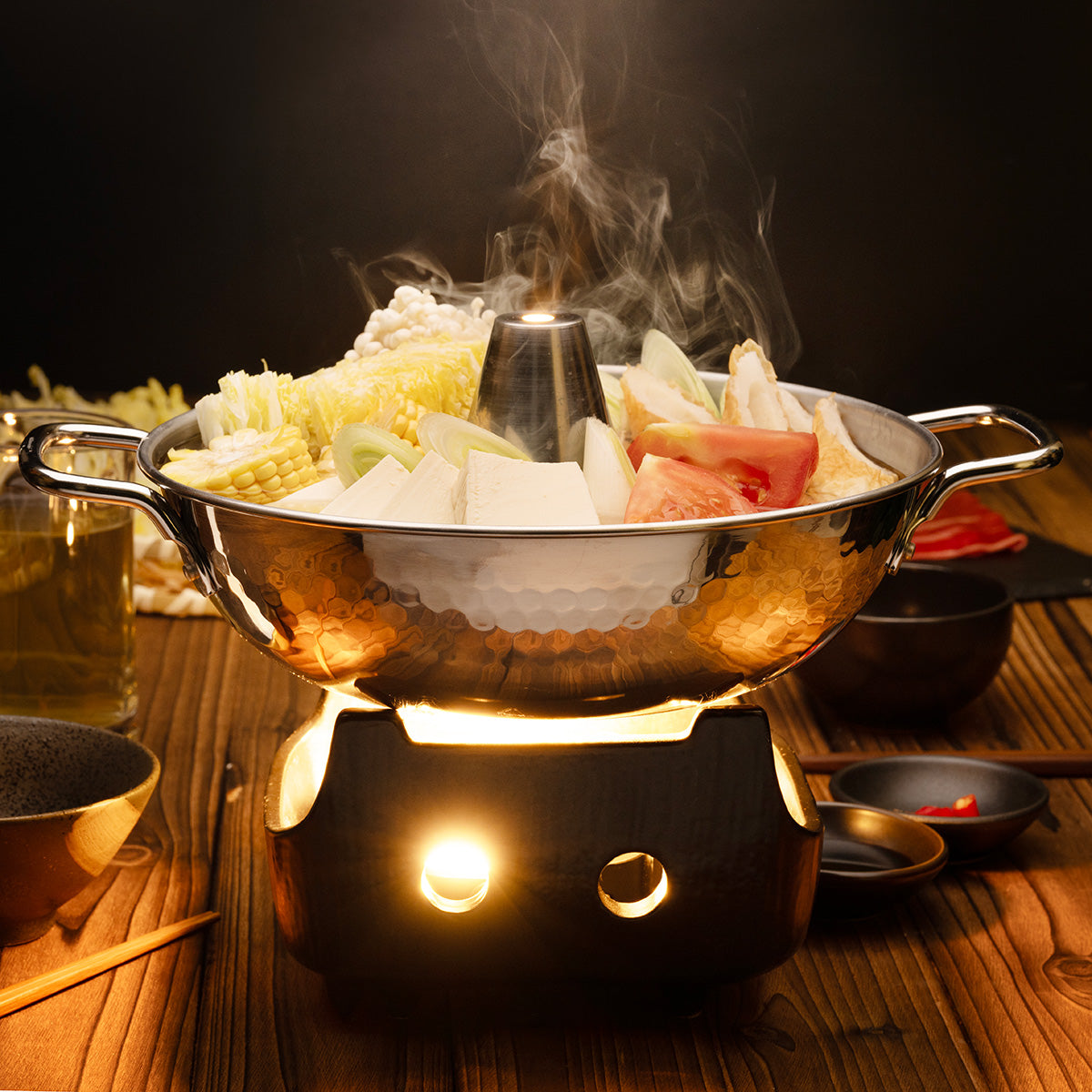 Japanese hot pot with hammered metal bowl and side handles, steaming vegetable boil