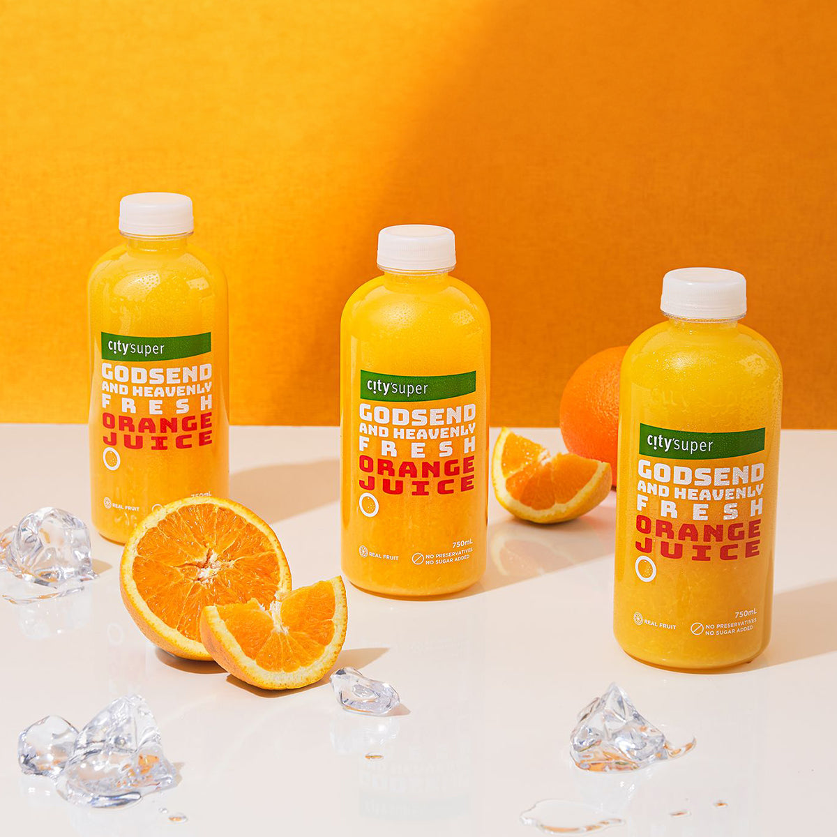 Orange juice bottles with ice and sliced oranges on a tabletop