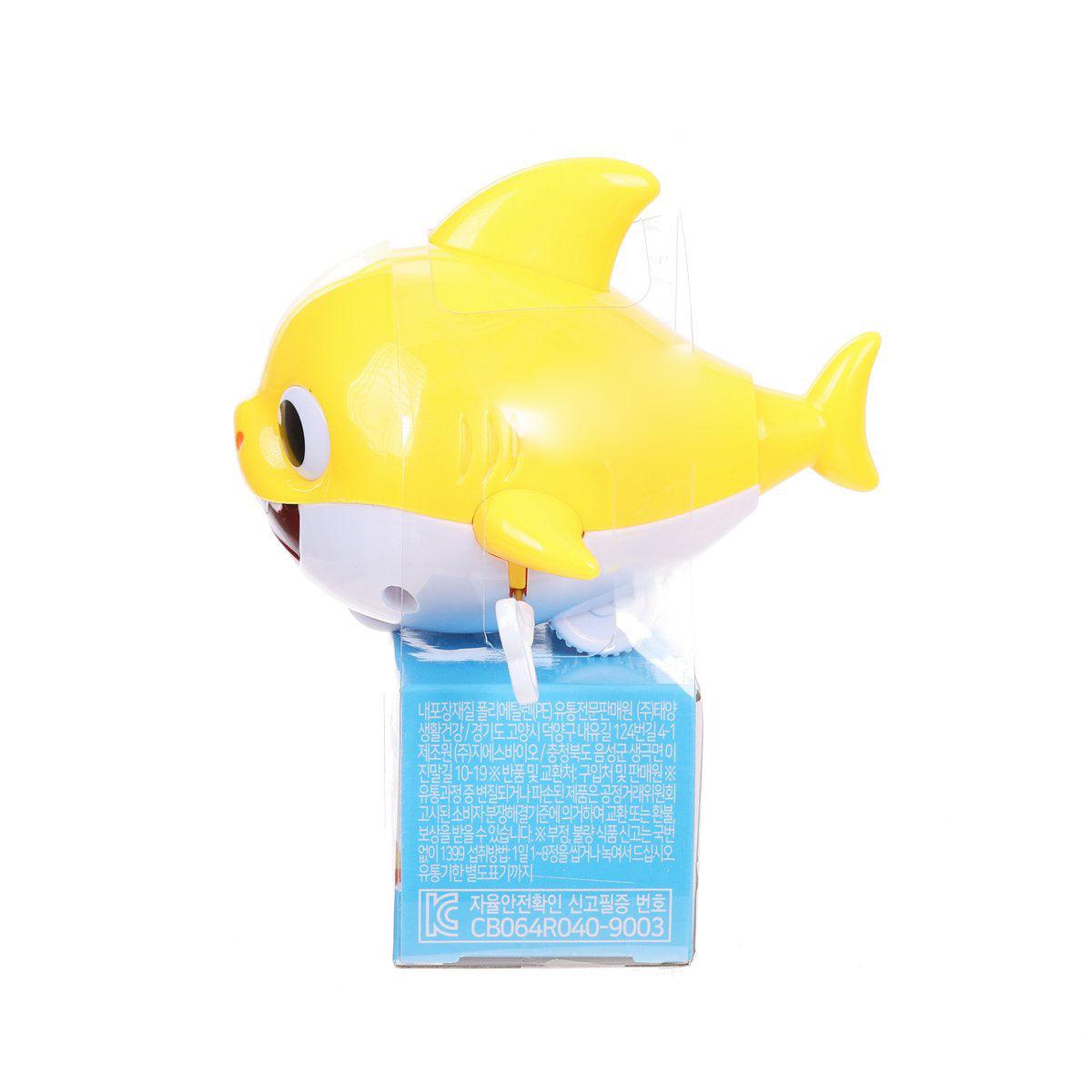 Yellow toy shark figure with big eye attached to a blue candy box