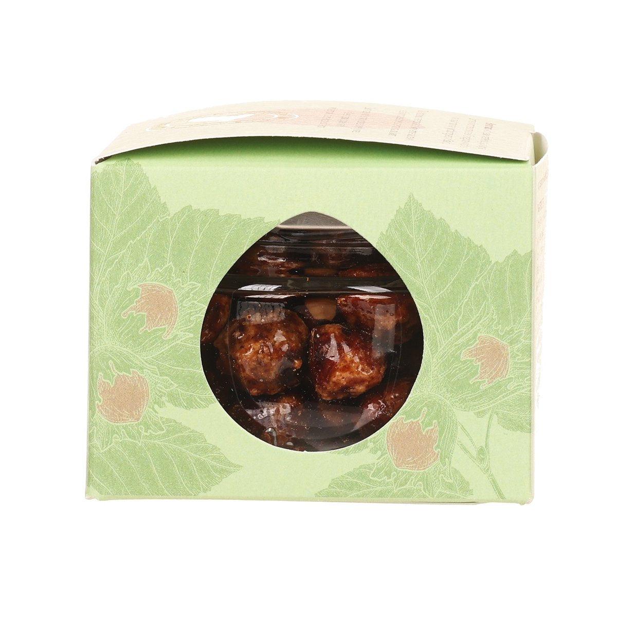 Green and cream box with circular window showing caramelised hazelnuts