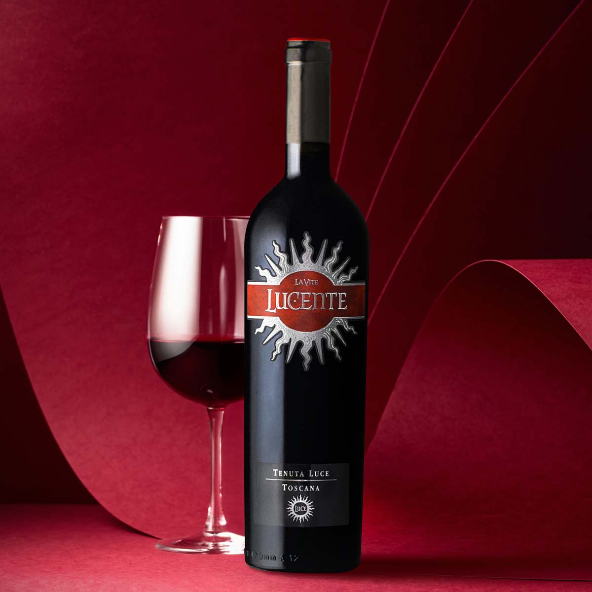 Lucente wine bottle with front label beside a wine glass, dark bottle, 750 mL