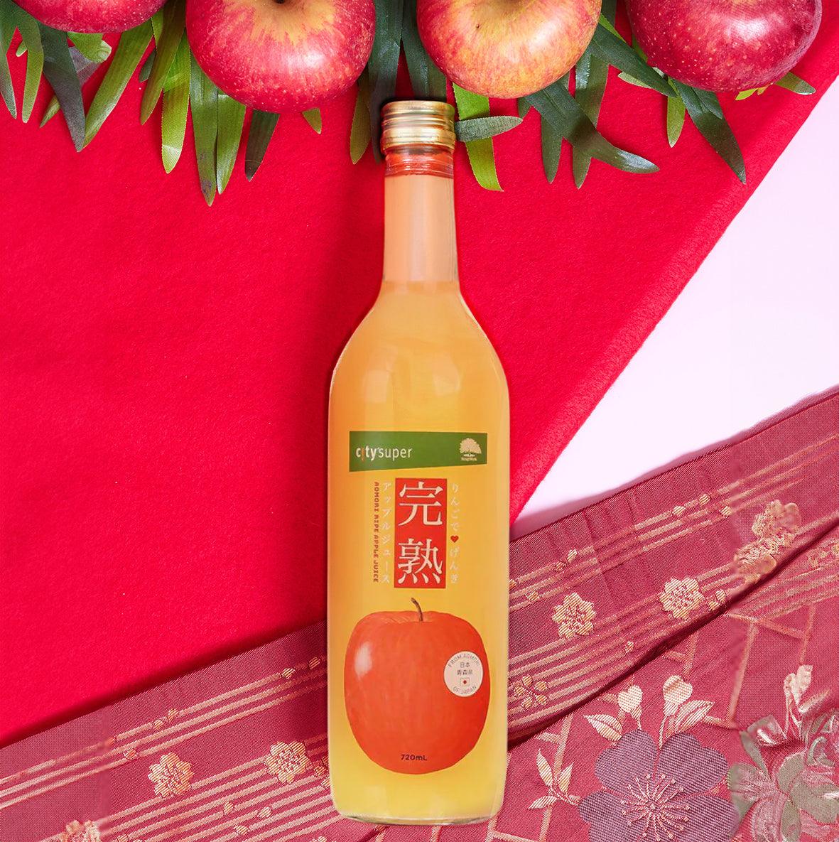Apple juice bottle with amber liquid and red apple label, with apples and green leaves
