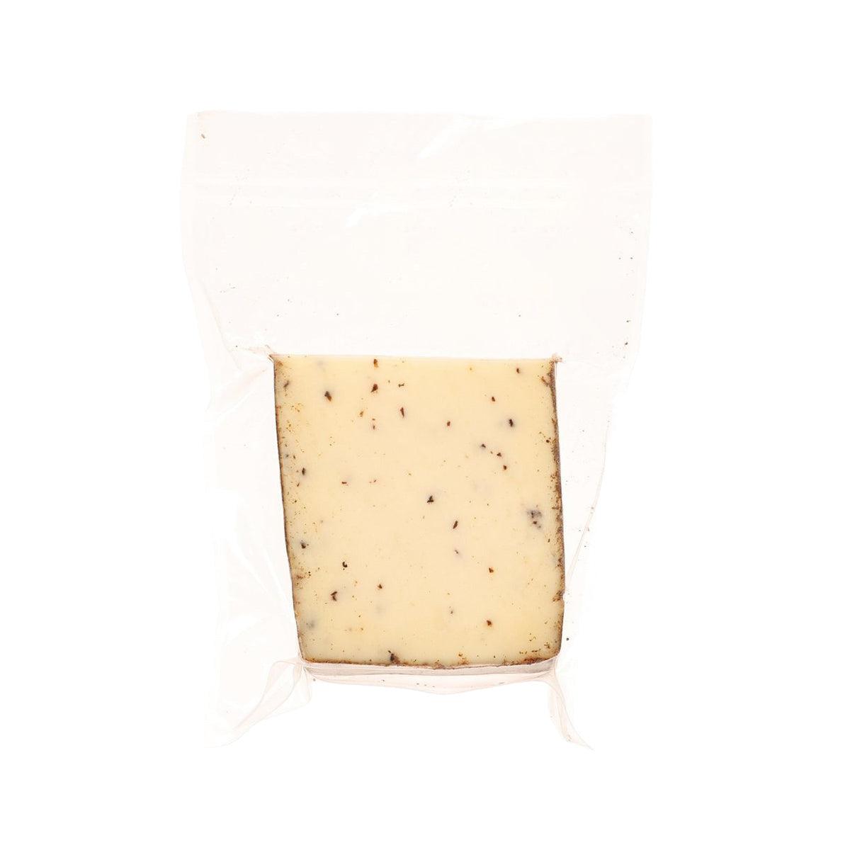 Perlagrigia truffles cheese wedge in white packaging, pale yellow with dark specks