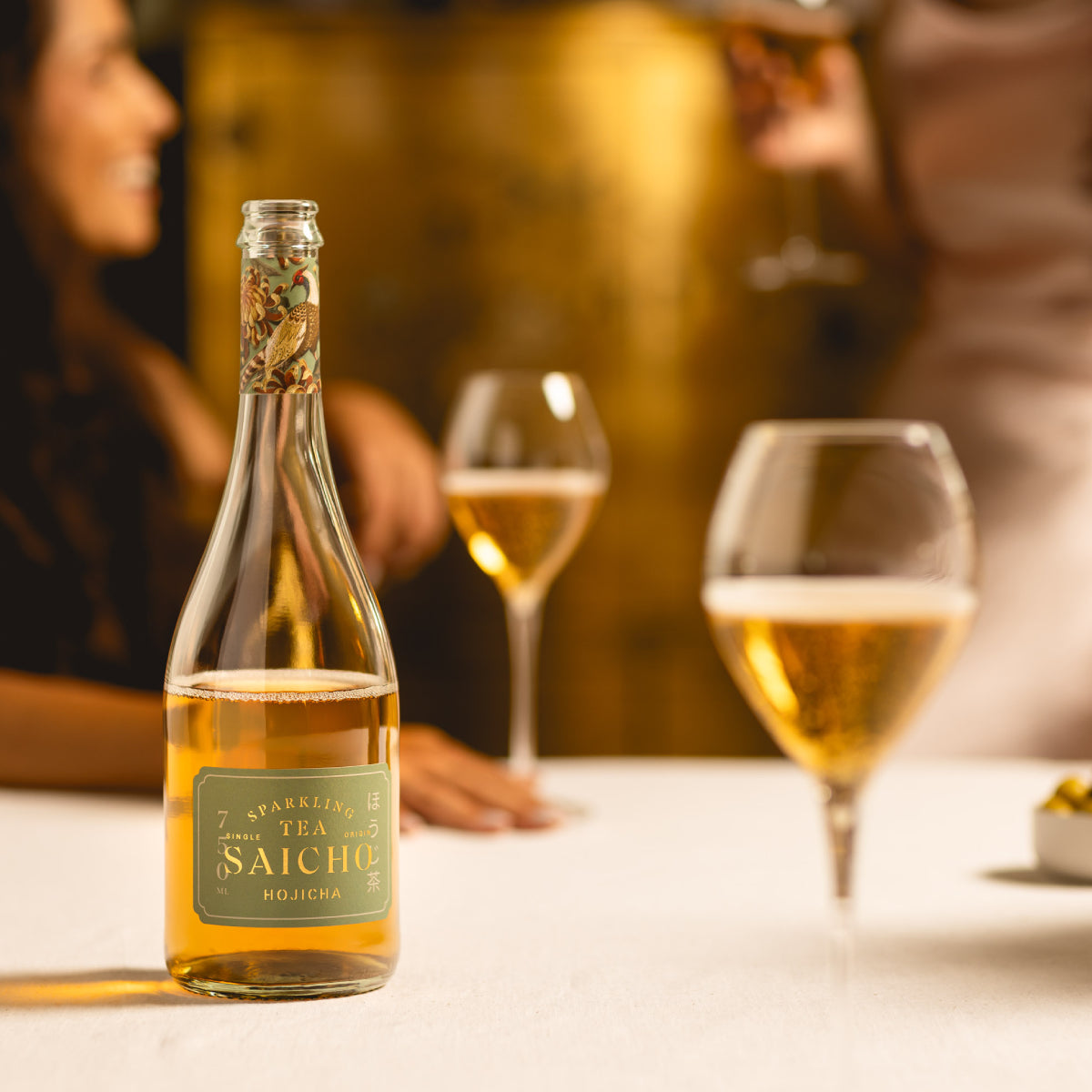 Sparkling tea bottle with two glasses of golden tea on a table