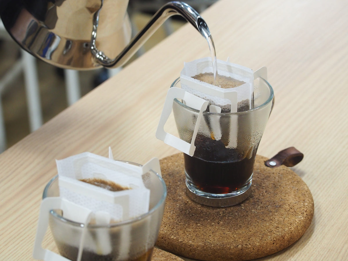 Coffee drip filters in use: two cups with brewed coffee and paper filter drippers