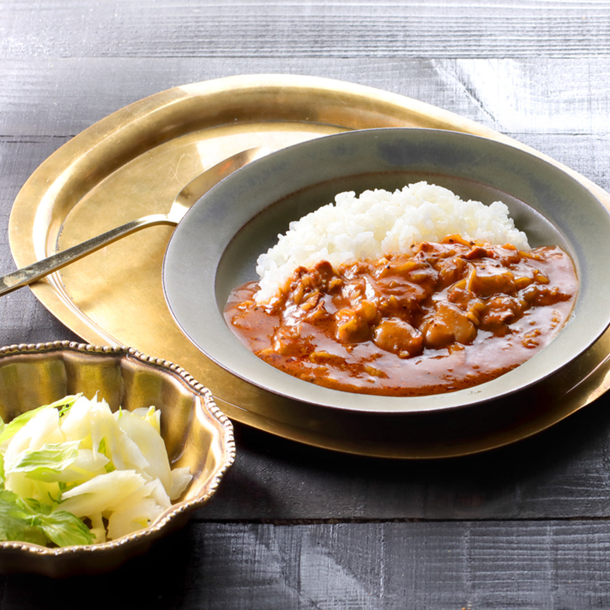 Beef stew served over white rice in a shallow bowl
