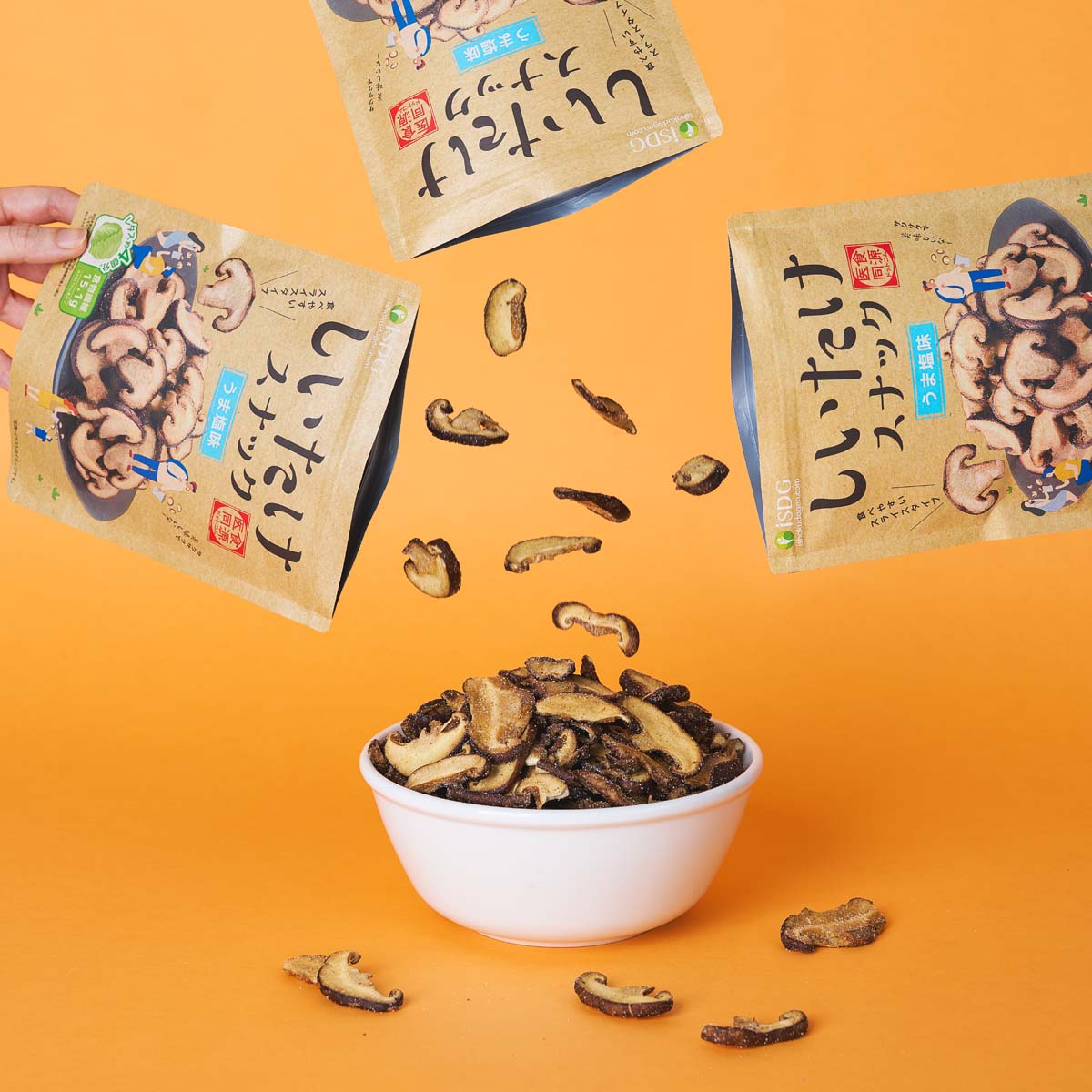 Strewn shiitake mushroom snack chips with open pouches and bowl of crackers