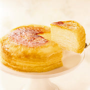 Plain mille-crepe cake with browned top, sliced and whole pieces on a plate