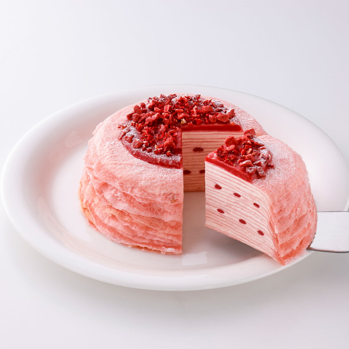 SUZETTE strawberry mille-crêpe cake, sliced on a plate, topped with strawberry bits