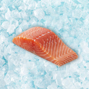 Frozen organic salmon fillet, pink-orange flesh with white fat lines, on ice