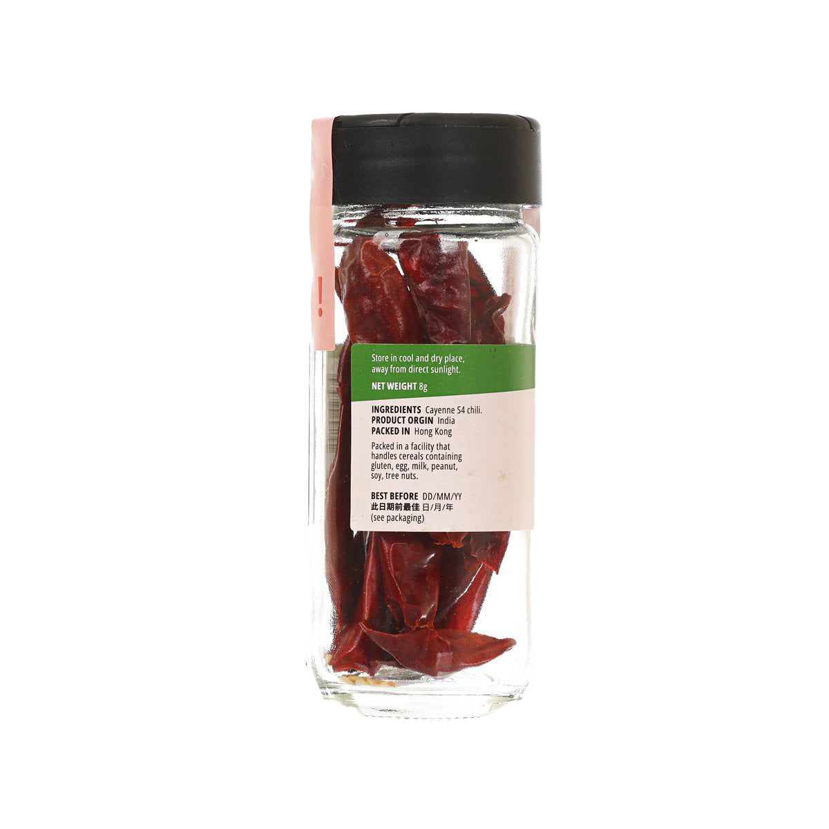 Glass spice bottle with black cap and dried whole cayenne chili, label facing back