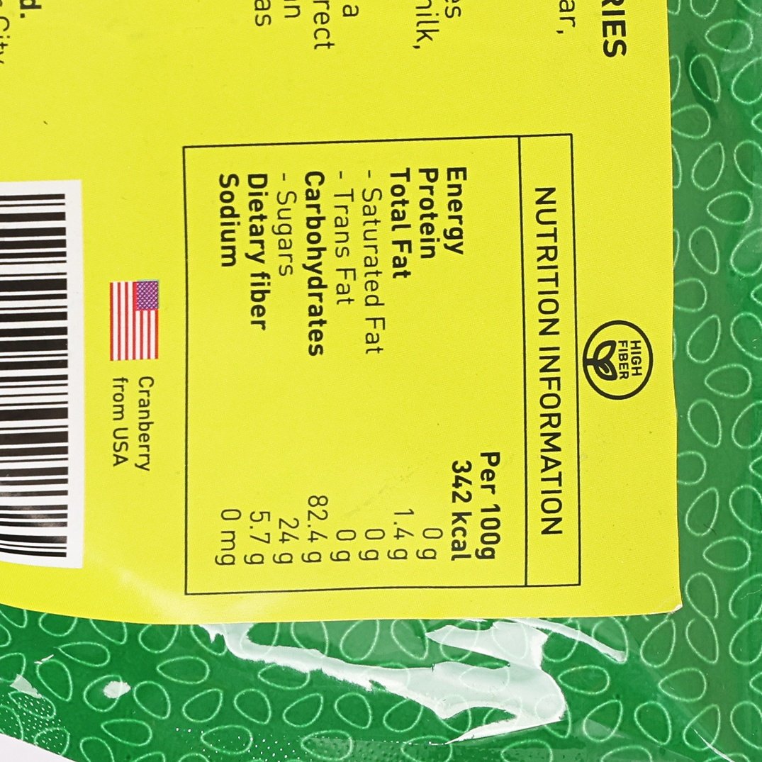 Nutrition information panel for dried cranberries, yellow label with per-100g values.