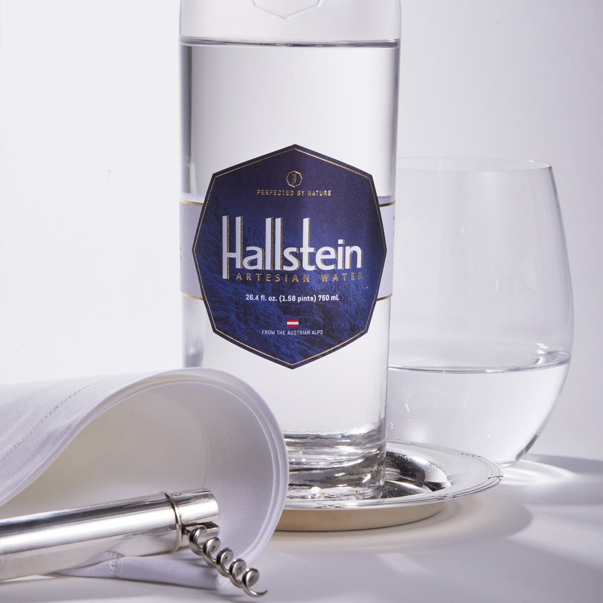 Clear glass water bottle with silver cap and blue Halstein label