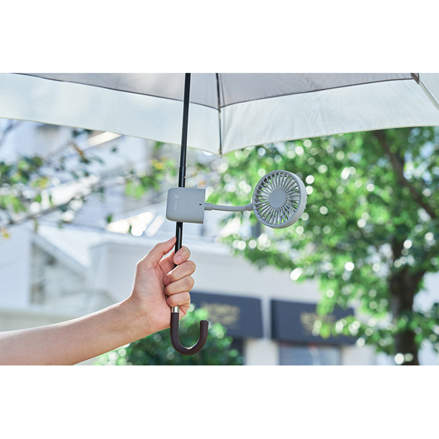 Portable slim grip fan clipped under umbrella, fan head visible with hook