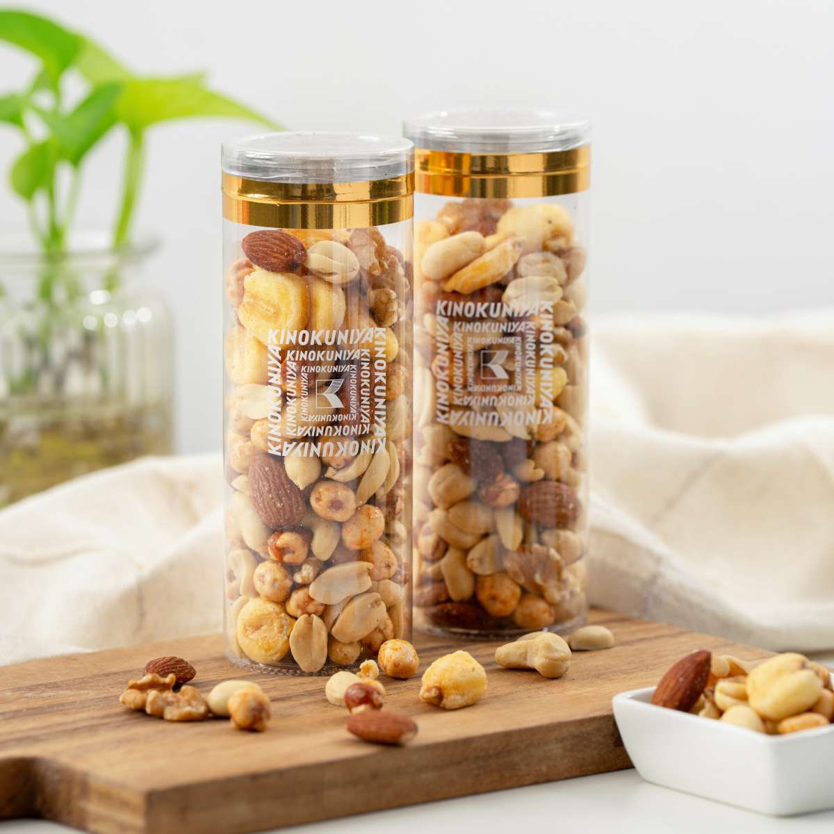 Two KINOKUNIYA mix nuts 110g jars with assorted nuts on wooden board and bowl